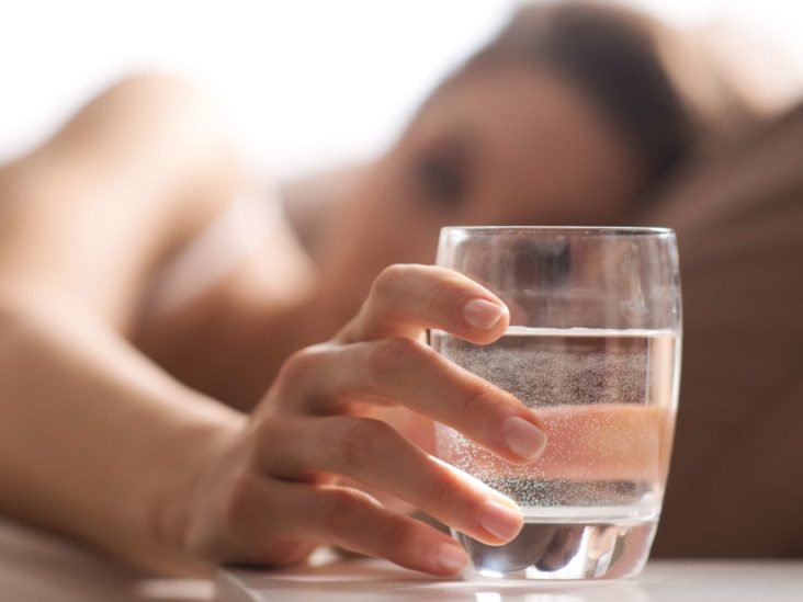 A woman about to drink water before going to sleep which is not good for digesion